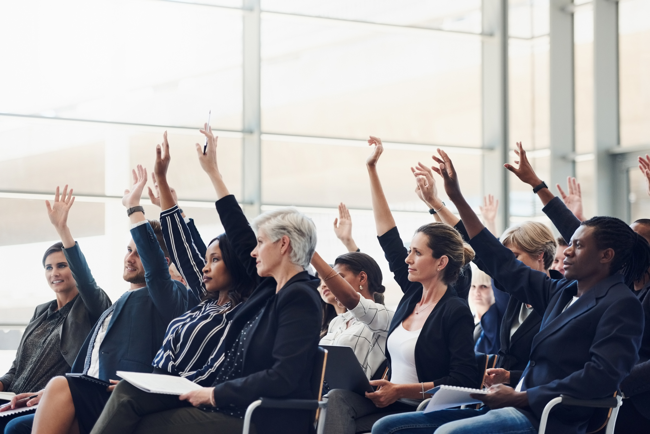 Group of Attendees Raising Hands to Ask a Question